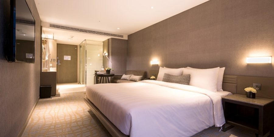 Interior of a hotel room with a bed, television, and a private bathroom area.